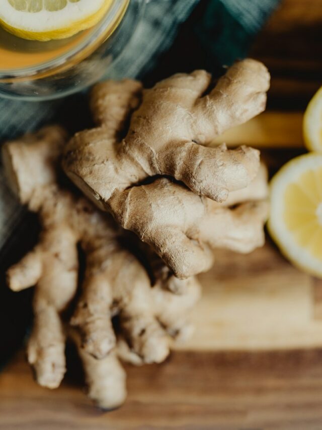 a glass of orange juice next to sliced lemons and ginger