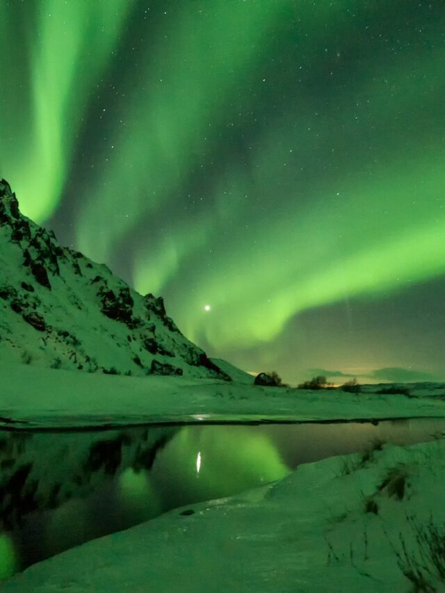 snow covered mountain with aurora borealis