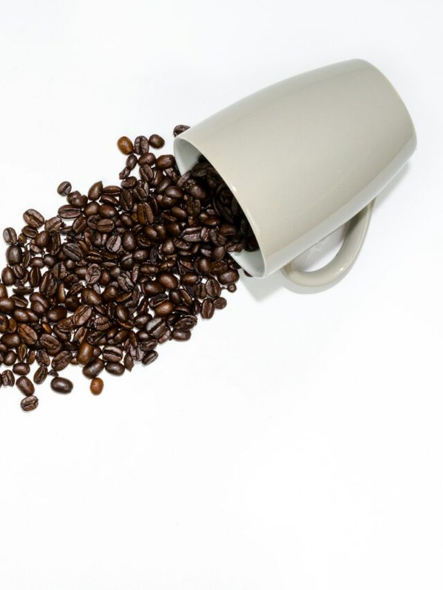 coffee beans beside gray ceramic mug