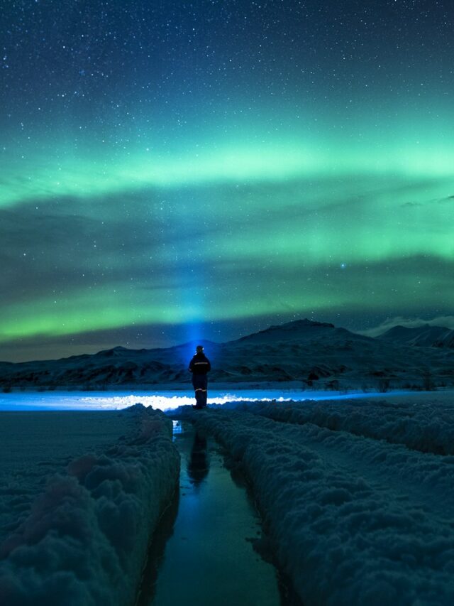 person standing on snow covered ground under green sky