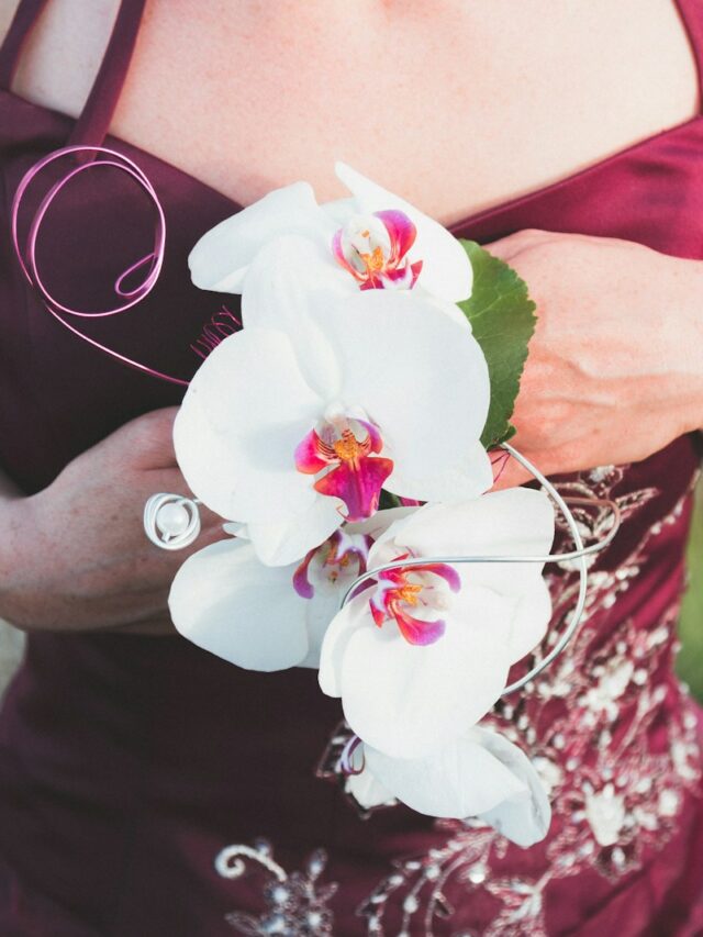 woman wearing red dress holding white orchids