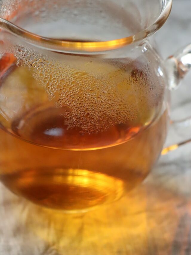 A glass tea pot filled with liquid on top of a table