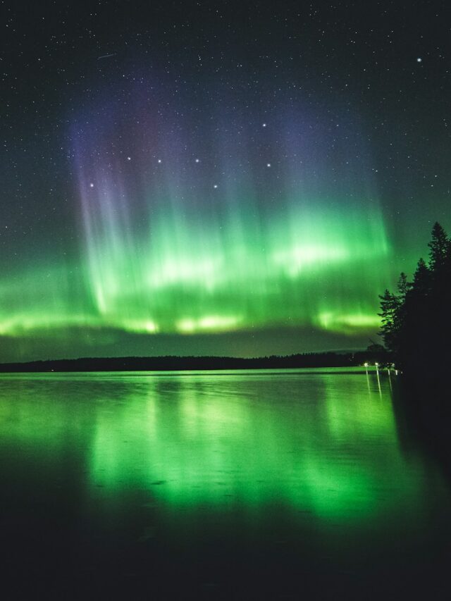 calm body of water under aurora lights