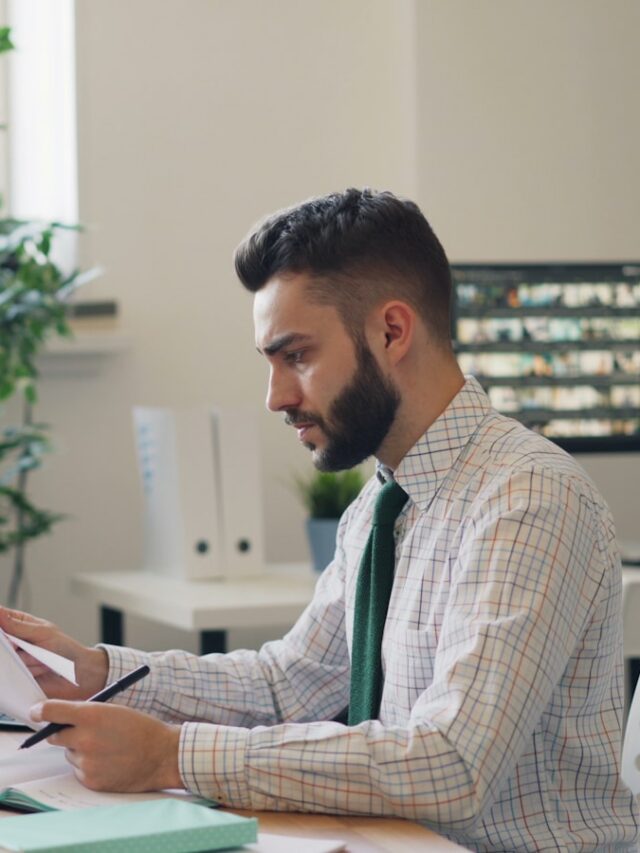 a man sitting at a desk with a laptop and papers