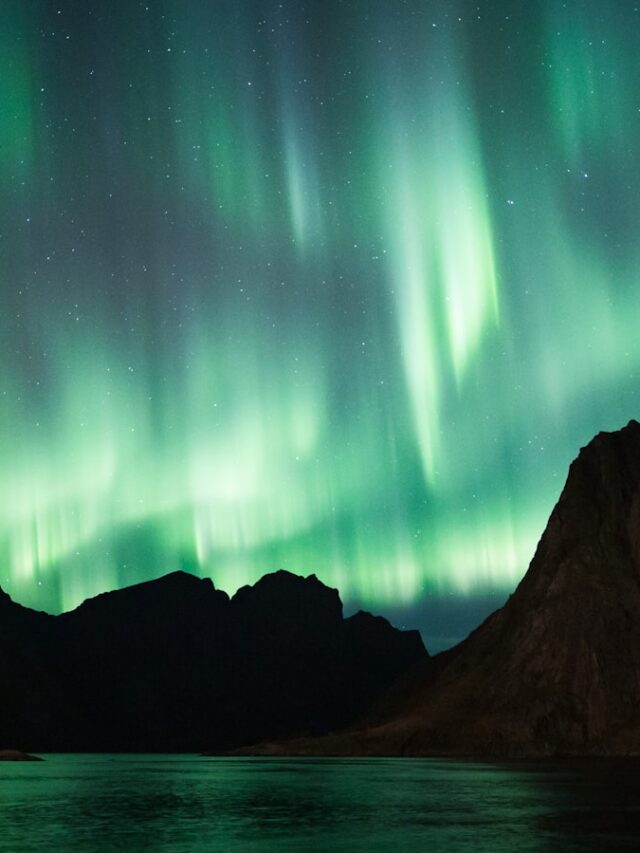 a green and purple aurora over a mountain range