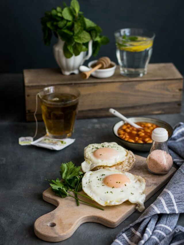 two fried eggs on brown chopping board near spices