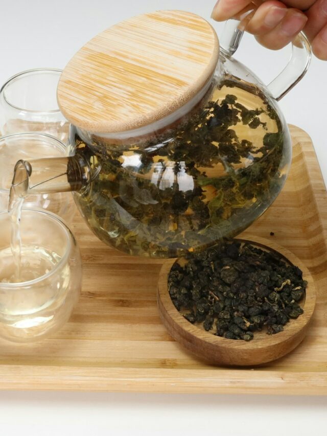 a person pours tea into a glass pitcher