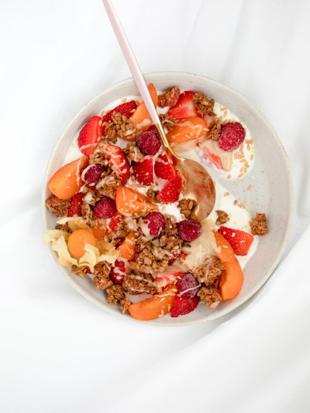 cereal with sliced strawberries and cream on white ceramic bowl