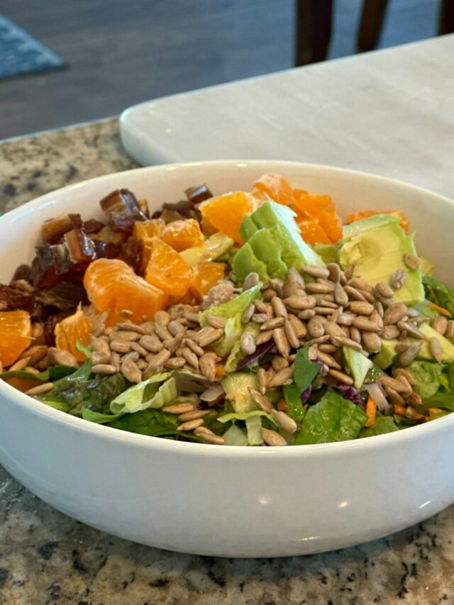 A bowl of salad next to a jar of dressing