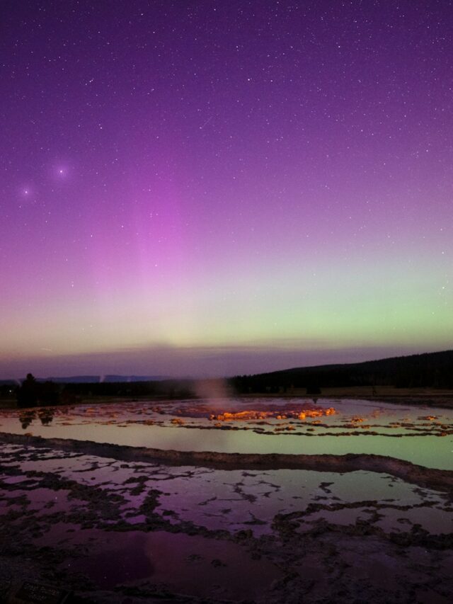 A purple and green aurora over a body of water