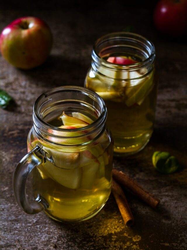 two drinking glasses filled with apple juice