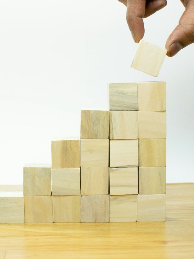 A person placing a piece of wood into a pyramid