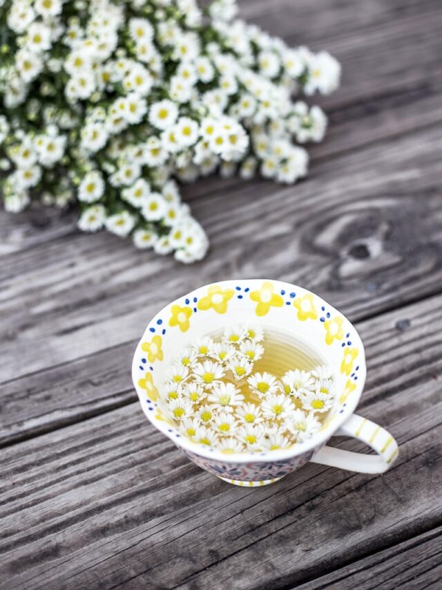 white and yellow cup with flowers on table